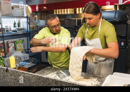 chef che spiega al suo studente come preparare l'impasto perfetto per la pizza. Foto di alta qualità Foto Stock