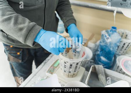 primo piano delle mani del falegname diluendo la vernice con un bastoncino di legno. Foto di alta qualità Foto Stock