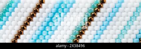 Foto macro dello sfondo con perline in stile boho. Motivo con perline di colore bianco, blu e bronzo. Foto Stock