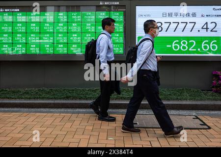 Tokyo, Giappone. 25 aprile 2024. Le persone passano davanti agli schermi che mostrano informazioni sul mercato azionario a Tokyo, Giappone, 25 aprile 2024. Giovedì, le azioni di Tokyo hanno chiuso in maniera significativamente più bassa, registrando una striscia vincente di tre giorni, mentre gli investitori hanno adottato misure per bloccare i guadagni tra le preoccupazioni sulle prestazioni aziendali. L'indice azionario Nikkei di riferimento del Giappone, la media azionaria Nikkei a 225 emissioni, è sceso di 831,60 punti, o 2,16%, da mercoledì a chiusura giornata a 37.628.48. L'indice TOPIx più ampio, invece, ha raggiunto 47,20 punti, ovvero il 1,74%, più basso a 2.663,53. Crediti: Zhang Xiaoyu/Xinhua/Alamy Live News Foto Stock