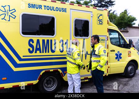 Un camion della struttura mobile di emergenza e rianimazione (SMUR) di Tolosa, con infermieri di fronte durante il Service d'Aide Medicale urgente (SAMU - servizi di assistenza medica urgente) i dipendenti in tute hazmat partecipano ad un esercizio nel centro di simulazione ambientale e neurosensoriale (SENS), un progetto Cupola di 140 m² che mira a esporre e formare i professionisti della salute attraverso la simulazione ai sentimenti ambientali, sensoriali ed emotivi avvertiti in una situazione di crisi a Tolosa, nel sud-ovest della Francia, il 25 aprile 2024. La cupola è in grado di realizzare gli scenari più realistici possi Foto Stock