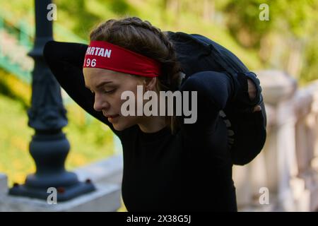 La giovane donna Ucraina porta un sacco di sabbia sulla schiena alla gara Spartan Race di Kiev - 20 aprile 2024 Foto Stock