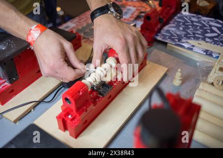 Mani di un uomo che lavora su una piccola macchina per tornitura su un tavolo in officina Foto Stock