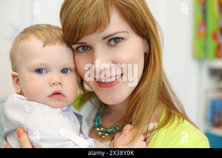 Una bella giovane madre posa con il suo piccolo carino figlio in camera, poco profondo Foto Stock