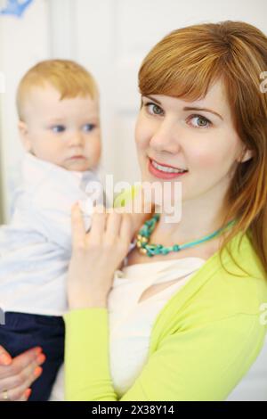 La bella madre posa con il suo piccolo figlio carino in camera, concentrati sulla donna Foto Stock