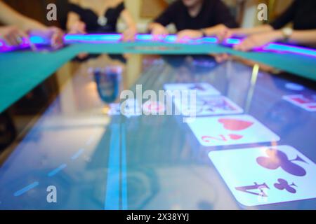 Tavolo elettronico nel casinò moderno e mani di quattro giocatori fuori fuoco Foto Stock