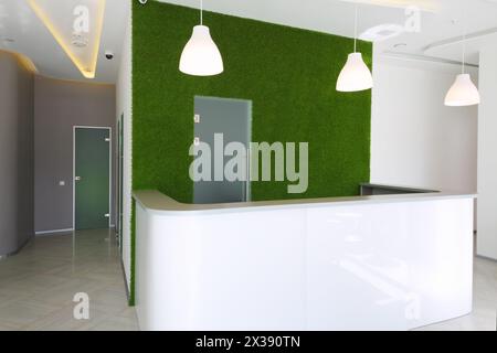 Sala ricevimento vuota con scrivania, prato verde nel centro affari Foto Stock