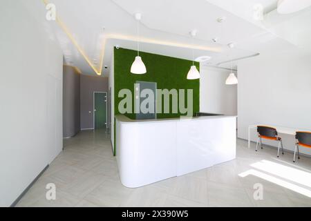 Sala ricevimento vuota e luminosa con scrivania, parete verde nel centro affari Foto Stock