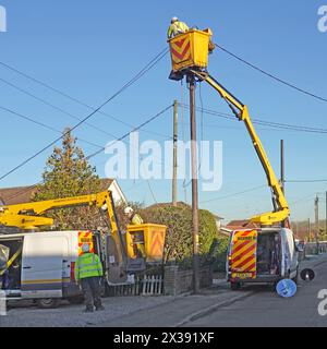 Ingegneri elettrici che lavorano in sollevatori residenziali per carrozzerie che sostituiscono i cavi elettrici sospesi nelle giornate invernali del cielo azzurro Inghilterra Regno Unito Foto Stock
