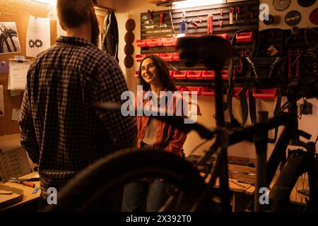 Una coppia innamorata riposa in garage dopo aver riparato la bicicletta. Uno sguardo da uomo a una donna innamorata Foto Stock