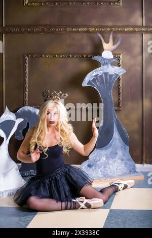 Ballerina in corona e scarpe pointe in studio con figure scacchistiche di cartone Foto Stock