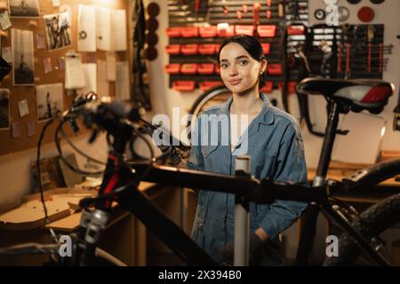 Ritratto di una bella giovane meccanica che si diverte mentre ripara le biciclette in un'officina. Foto Stock