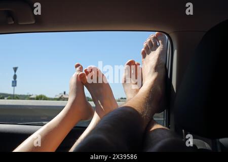 Due coppie di gambe fuori dai finestrini in auto in estate Foto Stock