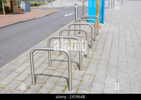 Portabiciclette vuote su un marciapiede di pietra lungo una strada Foto Stock