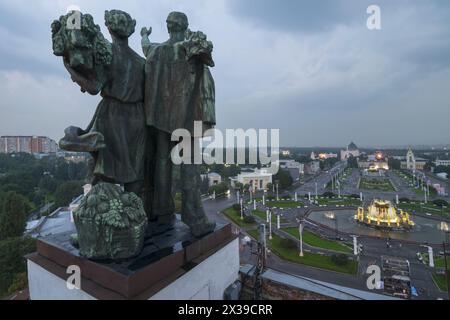 Scultura di donna e uomo sul padiglione principale e fontana a VDNKh in serata a Mosca, Russia Foto Stock