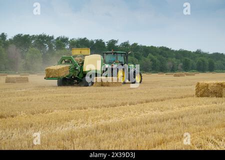 REGIONE DI KRASNODAR, RUSSIA - JUL 7, 2015: Il trattore produce mattoni pressati di paglia su campo giallo dopo il raccolto, nel 2015 nella regione di Krasnodar hanno raccolto r Foto Stock