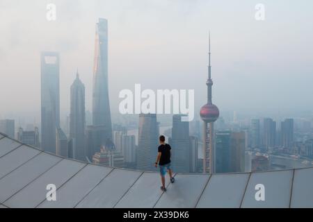 Man si erge sul tetto del grattacielo nella nebbiosa Shanghai la mattina presto, vista dalla White Magnolia Plaza Foto Stock