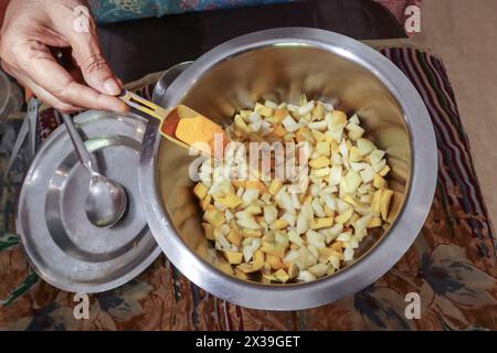 Processo di produzione artigianale di sottaceti di mango crudi utilizzando mango, polvere fredda rossa, curcuma e altre masala nella cucina indiana utilizzando utensili in acciaio inossidabile. Foto Stock