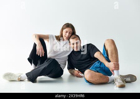 Due uomini seduti a terra, che condividono un momento d'amore. Foto Stock