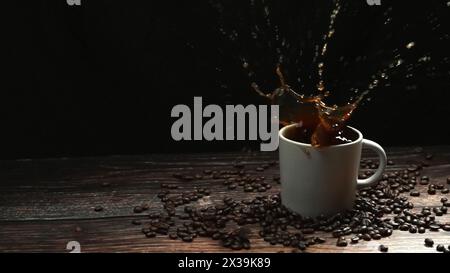Movimento ultrarapido di ghiaccio che cade nella tazza di caffè e spruzza con sfondo nero separato. Primo piano della goccia di zucchero nell'espresso Foto Stock
