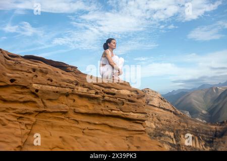 donna sportiva seduta sulle rocce che guarda la vista delle montagne, che si allontana da tutto, che reimposta lo stress Foto Stock