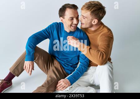 Due uomini in abiti casual seduti da vicino su una superficie bianca. Foto Stock