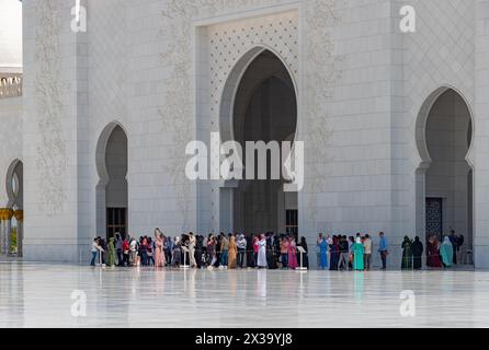 Una foto del cortile Sahan della grande Moschea Sheikh Zayed con una grande folla di visitatori vicino all'ingresso. Foto Stock