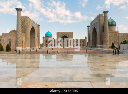 Splendida vista su Piazza Registan a Samarcanda, Uzbekistan. La Madrasa Ulugh Beg e la Madrasa Sher-Dor si riflettono sul pavimento bagnato. Lo è il Registan Foto Stock