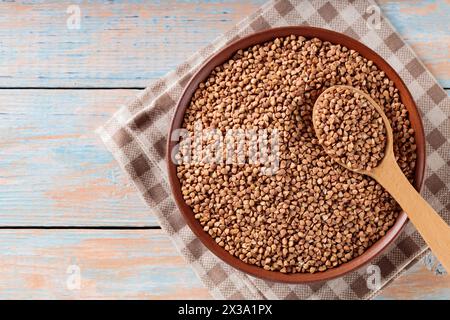 Coltivazioni di grano saraceno secche nella ciotola su tavolo in legno, dieta senza glutine, vista dall'alto, spazio per copie Foto Stock