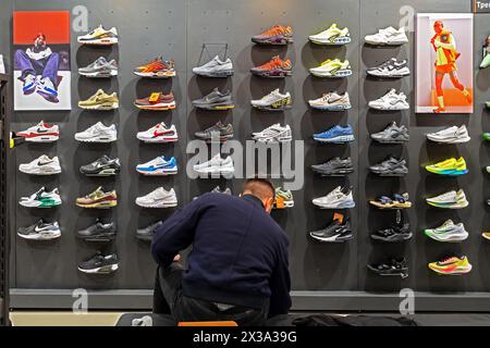 Un'ampia selezione di scarpe atletiche Nike sugli scaffali del negozio dell'azienda. Il cliente sceglie le sneakers per l'acquisto. Minsk, Bielorussia - 24 aprile 2024 Foto Stock