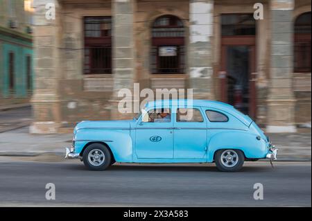 Auto d'epoca guidata lungo il lungomare sul Malecon di fronte ai vecchi edifici coloniali a l'Avana, Cuba. Foto Stock