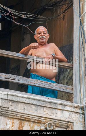 Un residente stava sul balcone della sua casa a guardare il mondo che passa, questo è un punto di vista comune nella città vecchia, l'Avana, Cuba Foto Stock