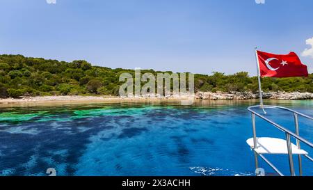 A bordo di una barca per esplorare le splendide coste turchesi di Bodrum. A poppa la bandiera della Turchia Foto Stock