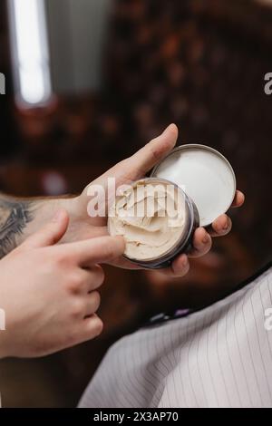 Un uomo barbuto si siede per un taglio di capelli in un barbiere Foto Stock