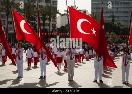 Izmir, Turchia - 23 aprile 2024: marcia dei giovani con le bandiere turche alle celebrazioni della sovranità nazionale e della giornata dei bambini, con lo Swissotel nel Foto Stock