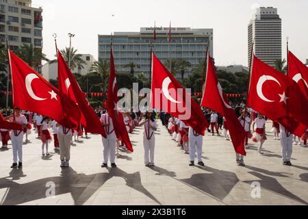 Izmir, Turchia - 23 aprile 2024: marcia dei giovani con le bandiere turche alle celebrazioni della sovranità nazionale e della giornata dei bambini, con lo Swissotel nel Foto Stock