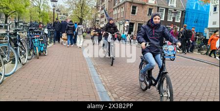 AMSTERDAM, NETHLANDS - 25 APRILE 2024 - le persone viaggiano in bicicletta in una strada di Amsterdam, Paesi Bassi, 25 aprile 2024. Foto Stock