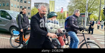 AMSTERDAM, NETHLANDS - 25 APRILE 2024 - le persone viaggiano in bicicletta in una strada di Amsterdam, Paesi Bassi, 25 aprile 2024. Foto Stock