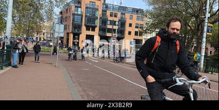 AMSTERDAM, NETHLANDS - 25 APRILE 2024 - le persone viaggiano in bicicletta in una strada di Amsterdam, Paesi Bassi, 25 aprile 2024. Foto Stock