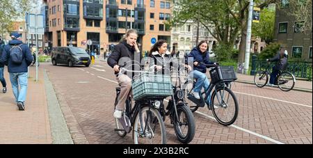 AMSTERDAM, NETHLANDS - 25 APRILE 2024 - le persone viaggiano in bicicletta in una strada di Amsterdam, Paesi Bassi, 25 aprile 2024. Foto Stock