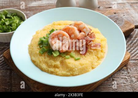 Piatto con gustosi gamberi freschi, pancetta, fiocchi d'avena e cipolla verde su tavolo di legno Foto Stock