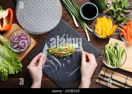 Donna che produce un rotolo a molla su un tavolo di legno con prodotti, vista dall'alto Foto Stock