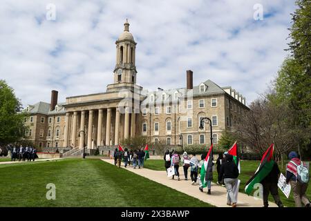 State College, Stati Uniti. 25 aprile 2024. I manifestanti pro-palestinesi portano bandiere palestinesi mentre camminano verso Old Main, nel campus della Penn State University. Gli studenti della Penn State per la giustizia in Palestina, insieme ad altre organizzazioni, tennero un'Università popolare per Gaza che includeva insegnamenti, gesso sul marciapiede e una manifestazione all'Old Main. Credito: SOPA Images Limited/Alamy Live News Foto Stock