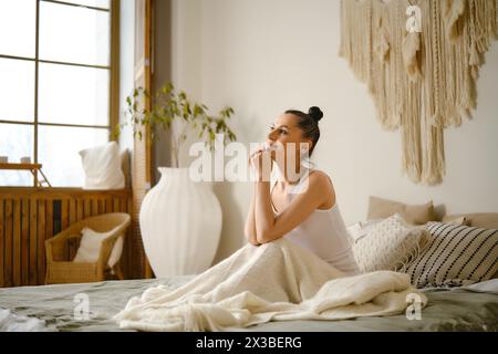 Bella donna seduta a letto e che fa progetti per la giornata Foto Stock