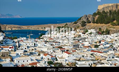 Case bianche di una città portuale con barche in mare e una fortezza sullo sfondo, Acropoli di Lindos, Lindos, Rodi, Dodecaneso, greco Foto Stock