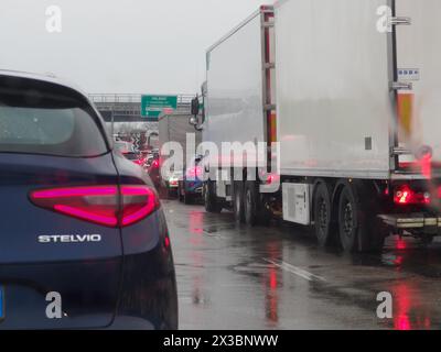 Traffico piovoso con un convoglio di camion e auto su un'autostrada bagnata, autostrada A1 A8 vicino a Milano, Italia Foto Stock