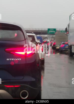 Concentrati sui semafori rossi di un'auto con traffico poco nitido sotto la pioggia su un'autostrada, A1 A8 vicino a Milano, Italia Foto Stock