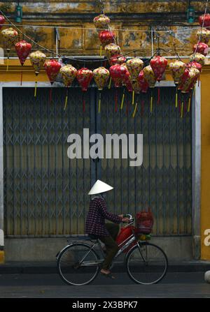 Una donna vietnamita in bicicletta nella città vecchia di Hoi An, Vietnam. Foto Stock