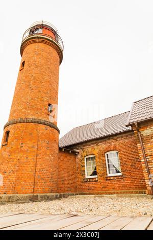 Un affascinante cottage in mattoni con un faro in legno arroccato sul suo tetto, che crea una facciata unica contro il cielo. Finestre, impianti e lavori in muratura Foto Stock