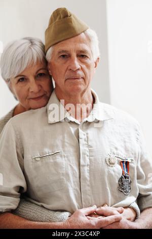 Militare, anziano e donna con veterano in uniforme con medaglia o orgoglio per la memoria del servizio di battaglia. Coppia anziana, esercito o pensionamento dal dovere a. Foto Stock